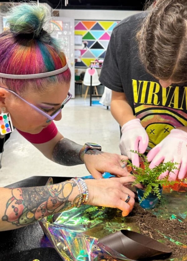 a teacher helps a student plant a fern